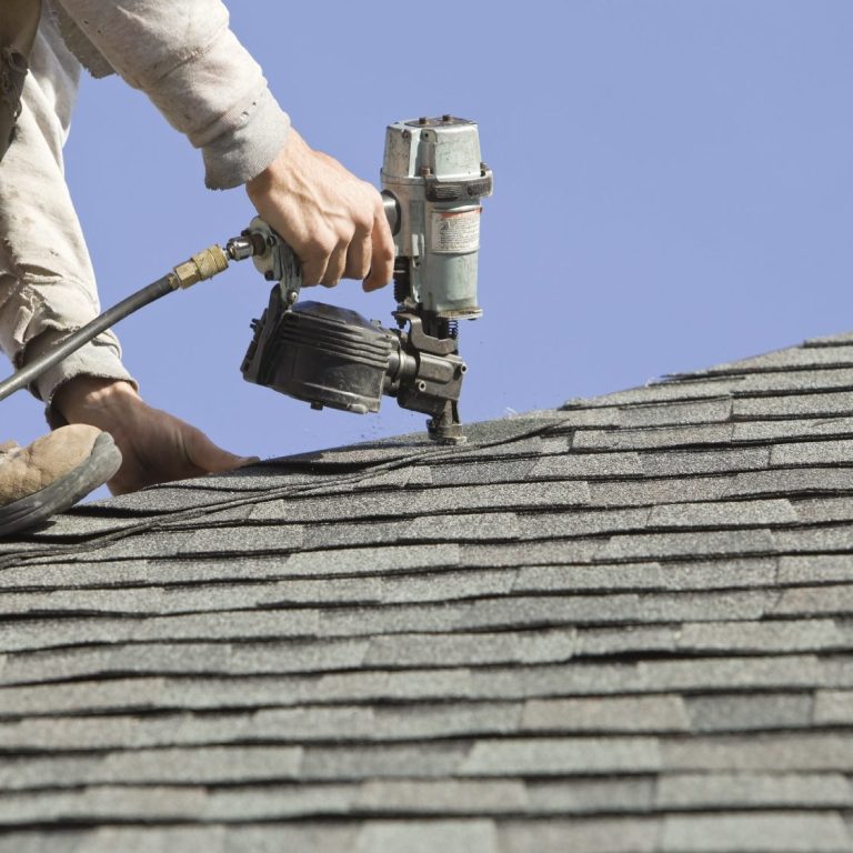 Contractor Roof Repair A person using a nail gun to install shingles on a sloped roof.