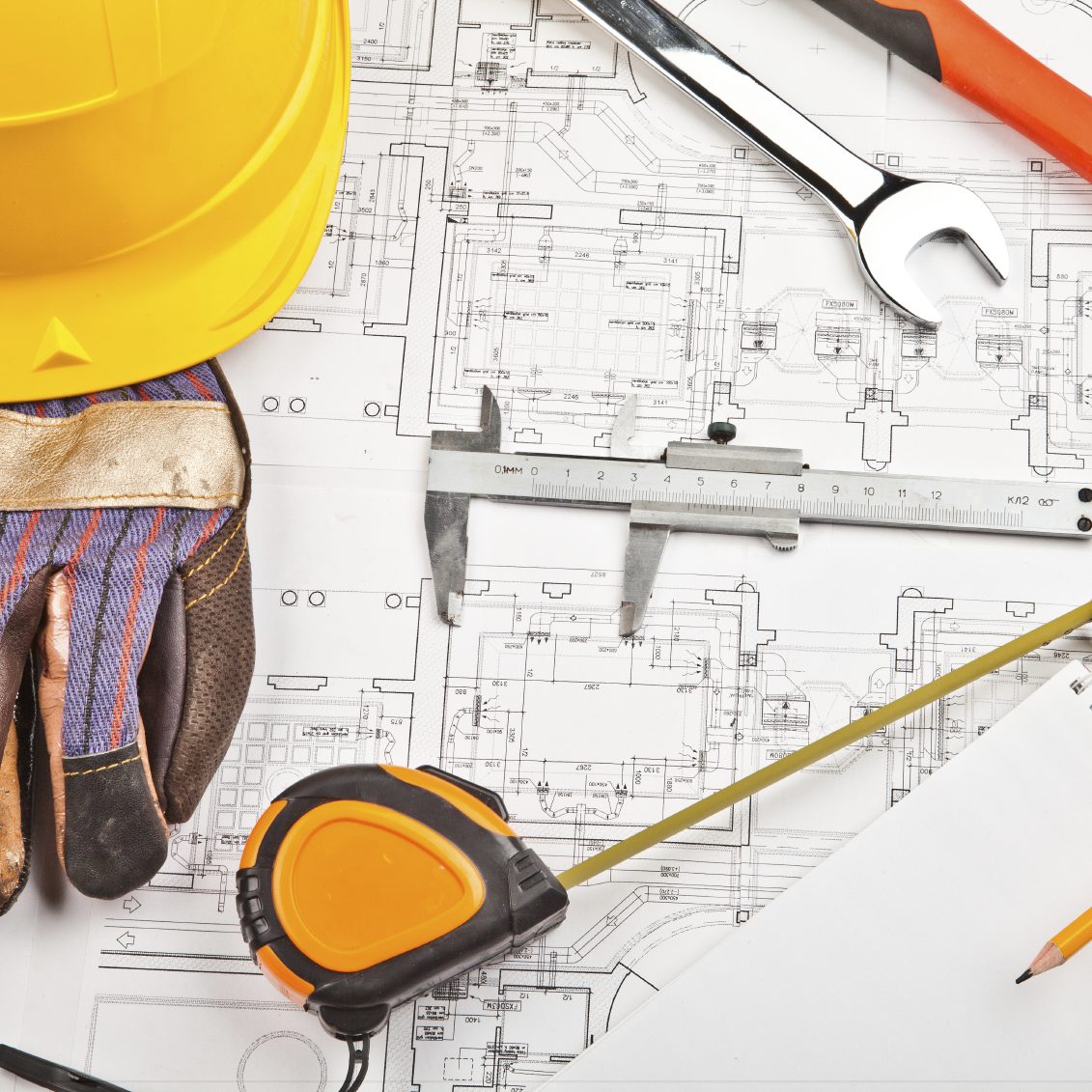 Construction Tools and Plans Construction tools and plans with a hard hat and gloves on a work surface.